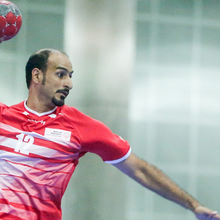 Handball player jumps up with the ball. 