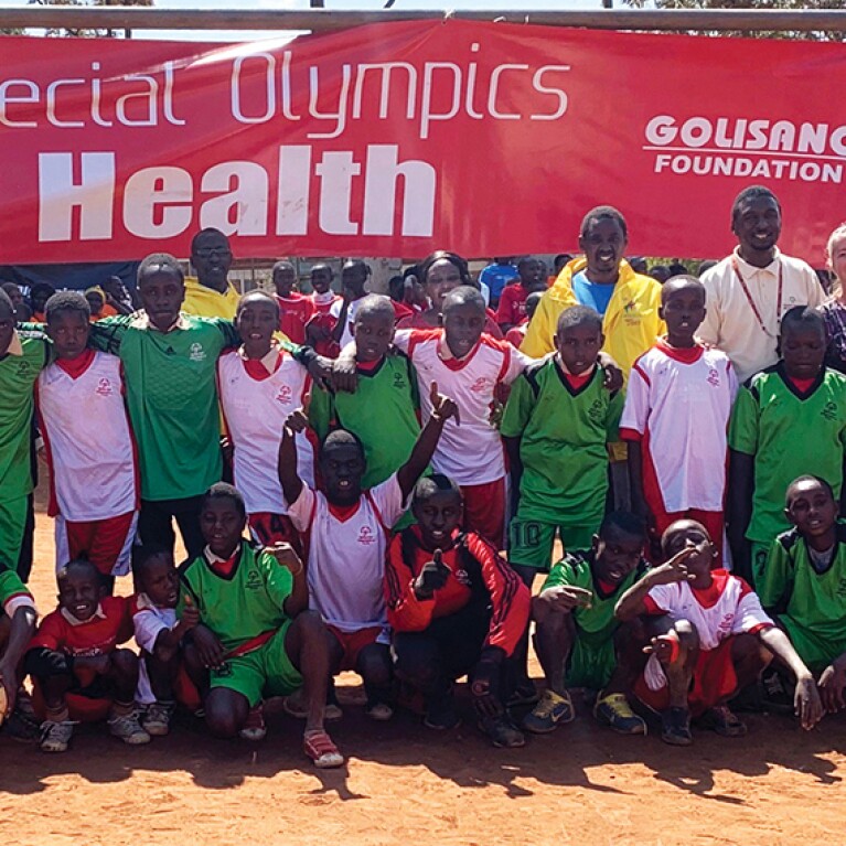 A group of athletes and Special Olympics representatives standing together in a group. The banner in the background reads: Special Olympics Health | Golisano Foundatoin