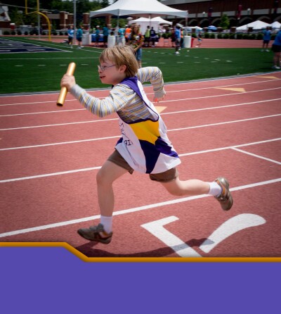 Athlete relay racing on a track with a baton in his hand. 