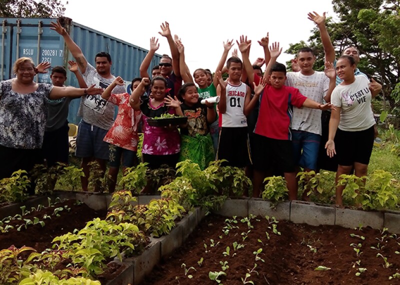 Group of people standing outside in front of a newly growing garden. 