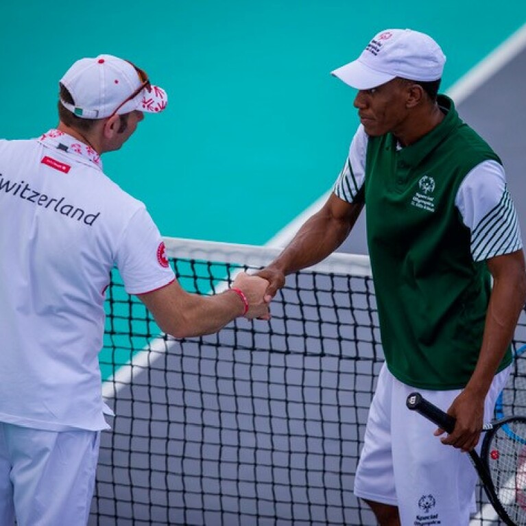 Two Special Olympics athletes shake hands at the end of a tennis match. 