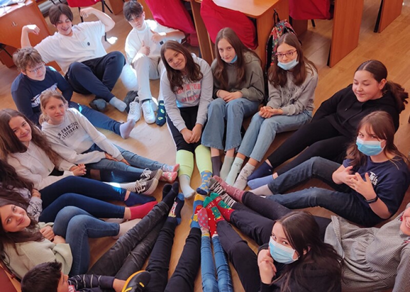 A group of students sitting in a circle with their feet together and showing off their socks. 